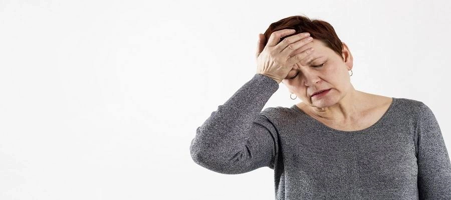 Mulher com a mão na testa com expressão de dor