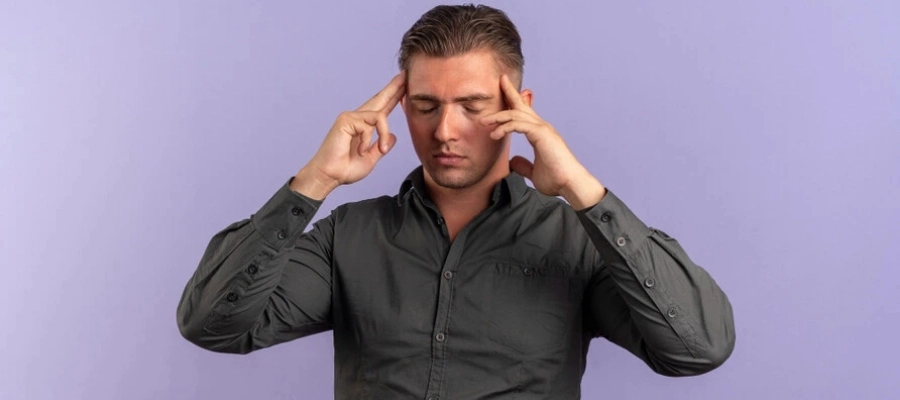 homem jovem sentindo dor segurando a cabeça com os dedos