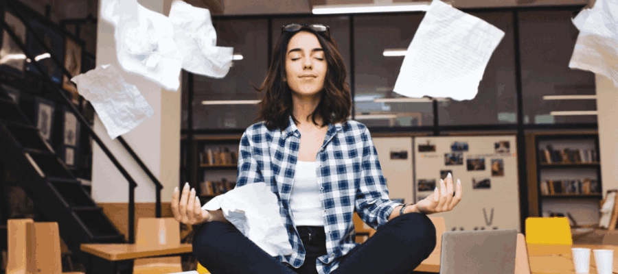 mulher jovem meditando sobre a mesa, cercada de papéis