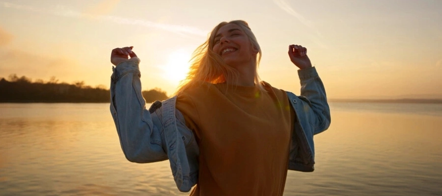 eng345 - mulher jovem sorridente e feliz com os braços abertos com uma lagoa ao fundo