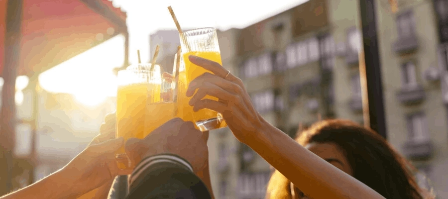 grupo de amigos brindando com copos com bebida laranja ao ar livre
