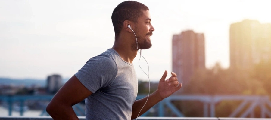 eng346 - homem esportista correndo na rua com camiseta cinza e fones de ouvido