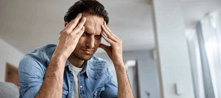 homem com a mão na cabeça, sentindo dor de cabeça na testa.