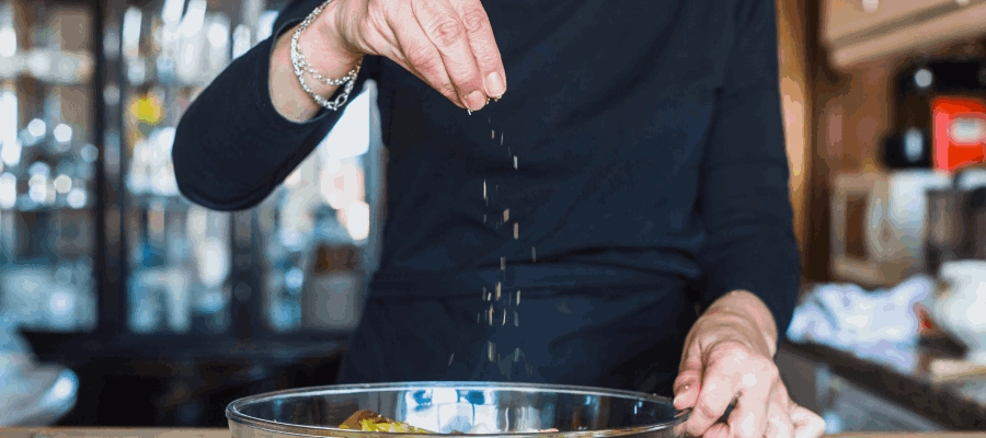 mulher colocando sal na comida