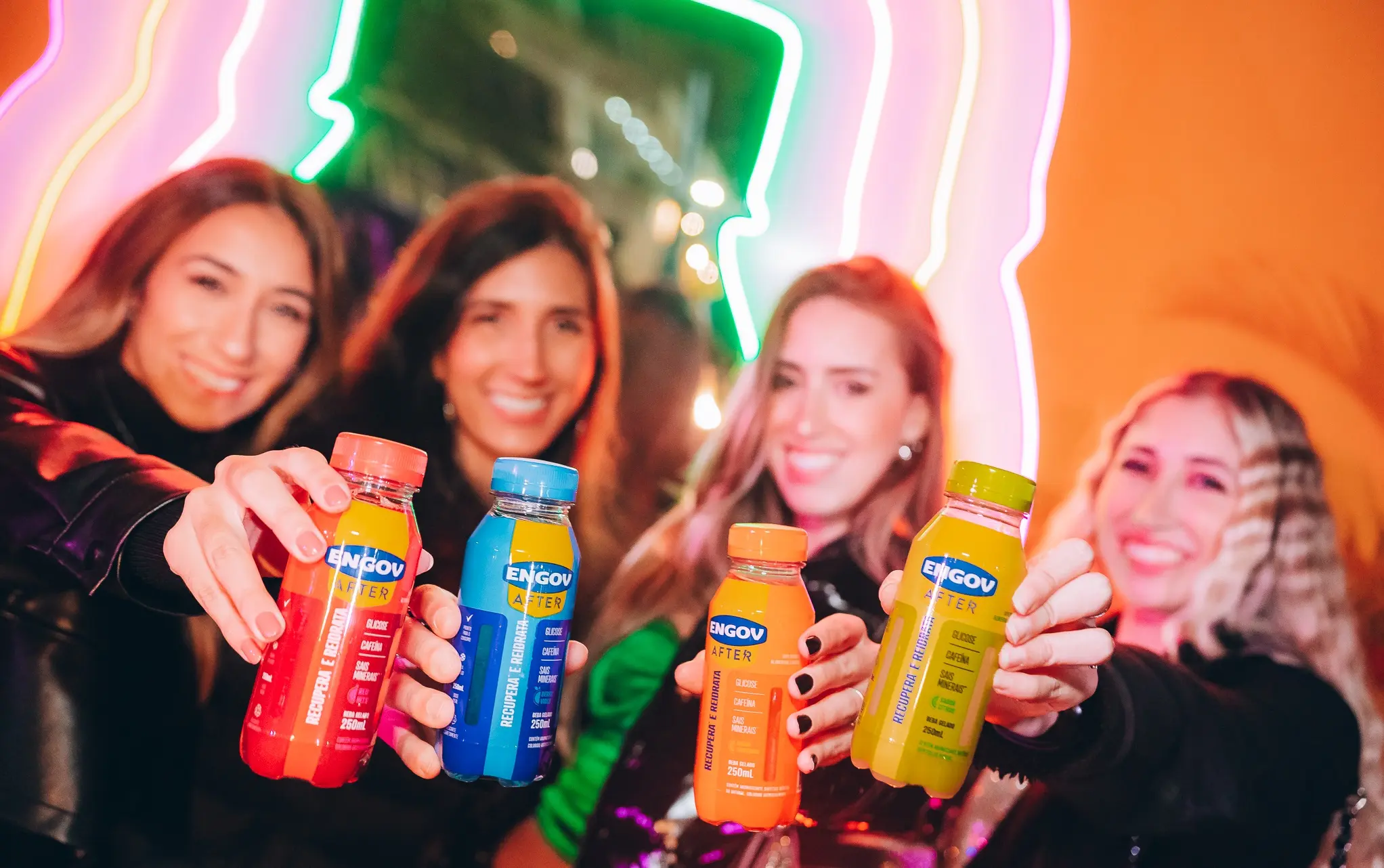 Quatro mulheres brancas sorrindo com garrafas de Engov After nas mãos.