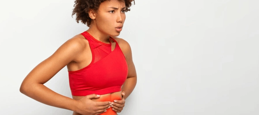 mulher negra com roupa esportiva sente desconforto no estômago e pensa em um remédio para azia