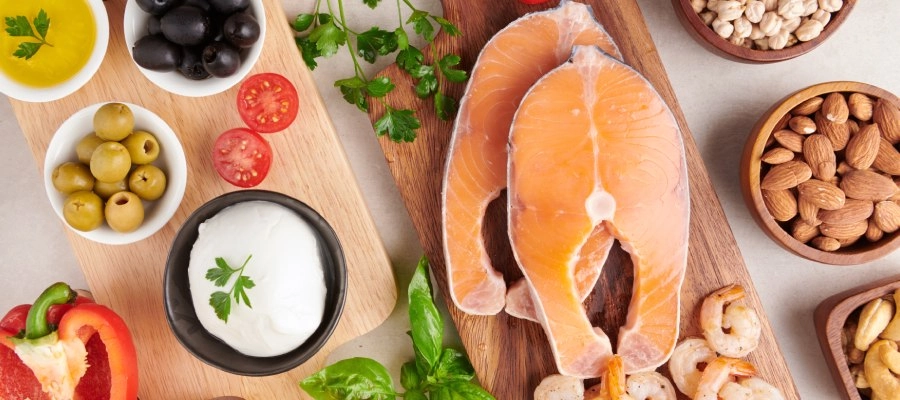 Mesa com alimentos fonte de colina, como azeitona, amêndoas, salmão e leite.